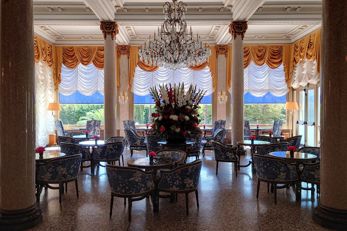 Grand Belle Epoque hotel lounge with chandelier, draped windows and upholstered seating - the operating business that sits behind every hotel valuation